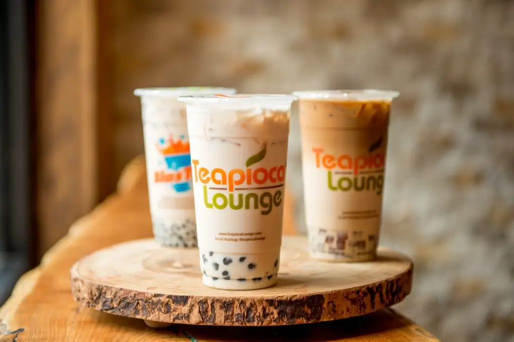 A Teapioca Lounge signature boba tea served in a clear cup with tapioca pearls, ice, and branded logo on the cup.