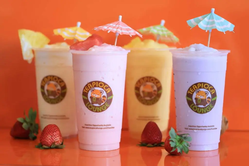 A colorful variety of Teapioca smoothies and boba drinks displayed on a wooden table.